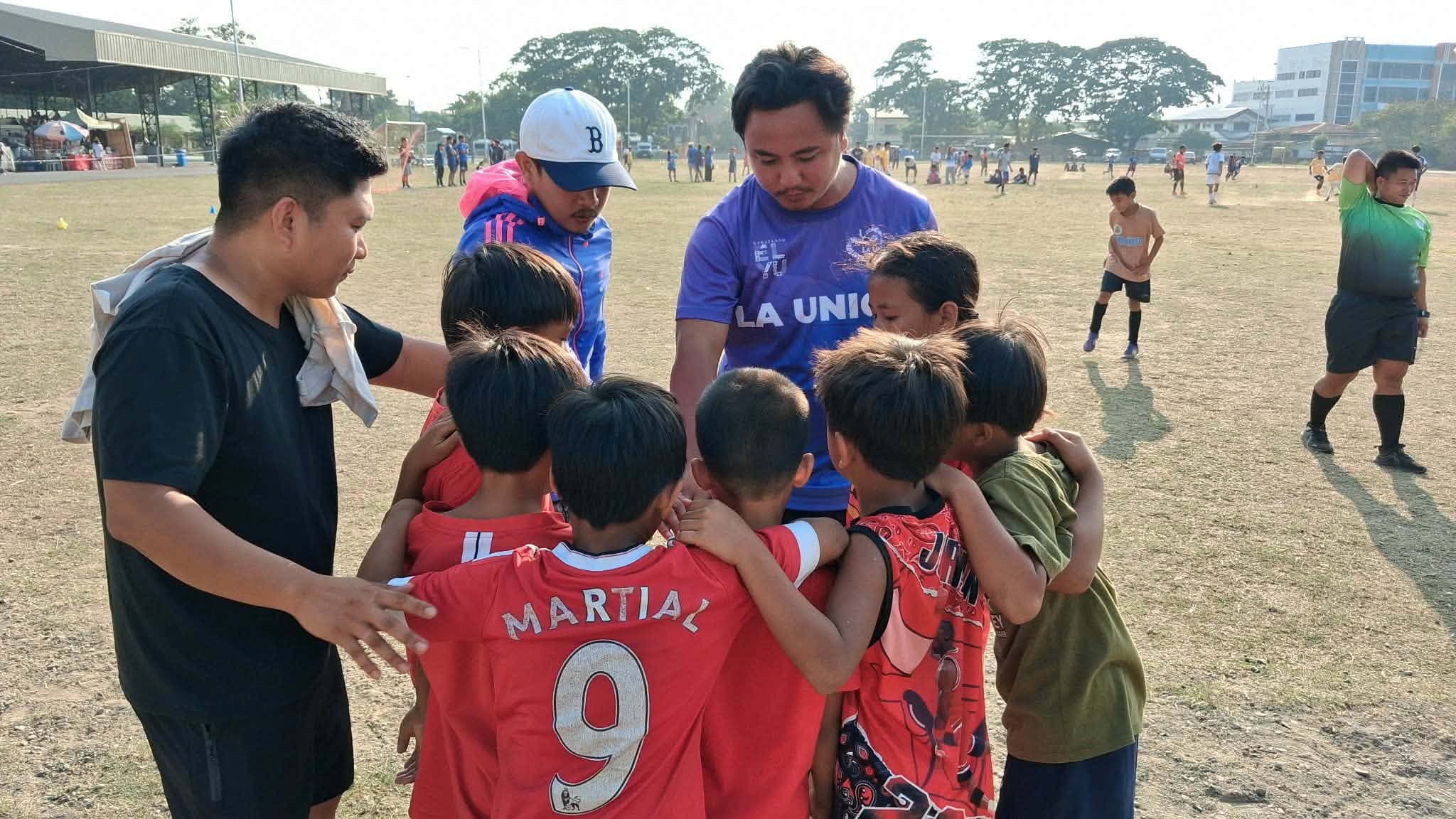 An AFFC coach talking to a huddle of young players before a match